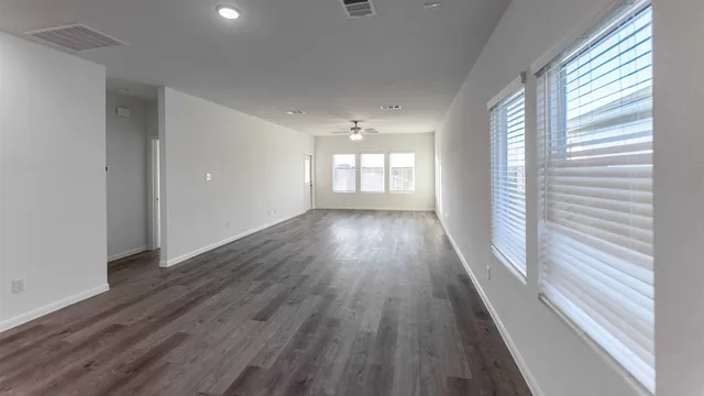 a view of empty room with wooden floor and fan