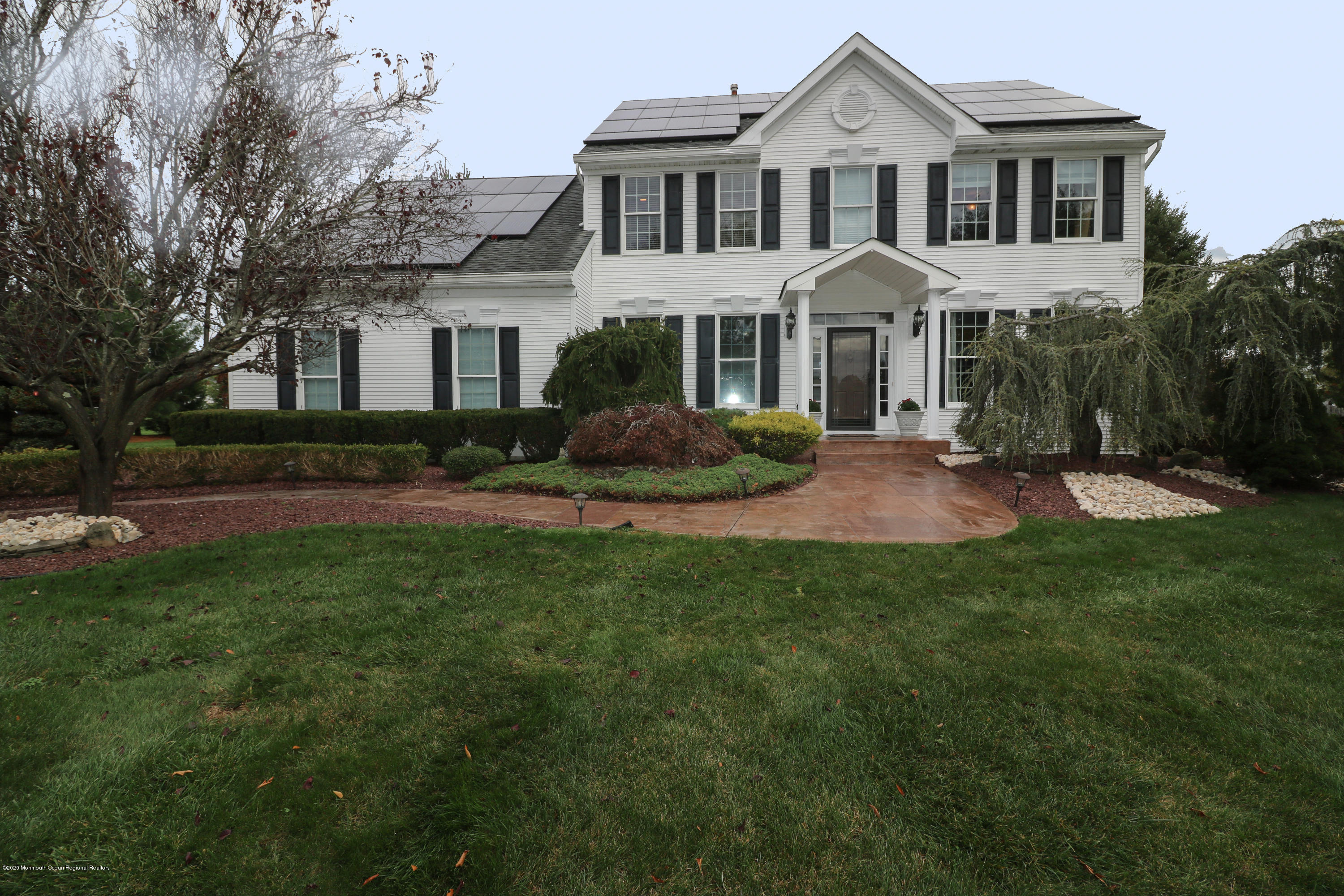 a front view of a house with a yard and trees