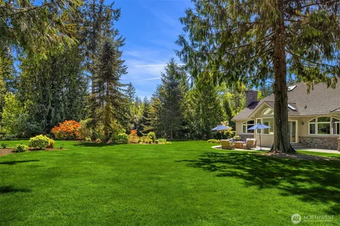 a view of a house with a big yard and potted plants and large trees
