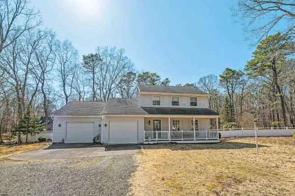 a front view of house with yard and trees in the background
