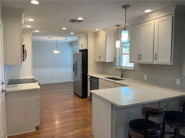 a kitchen with a sink a refrigerator and chairs
