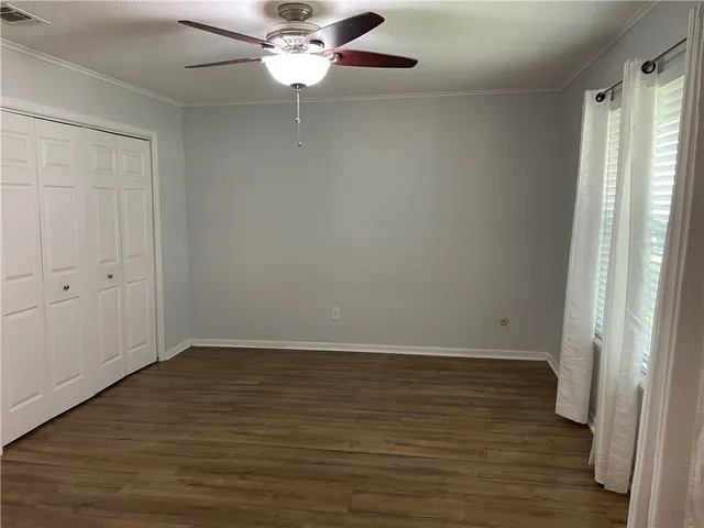an empty room with wooden floor fan and windows