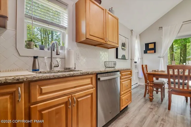 a kitchen with stainless steel appliances granite countertop a stove a sink a dining table and chairs with wooden floor