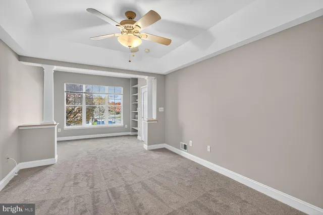 an empty room with windows and ceiling fan