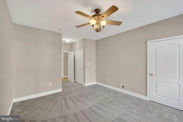 a view of an empty room with chandelier fan