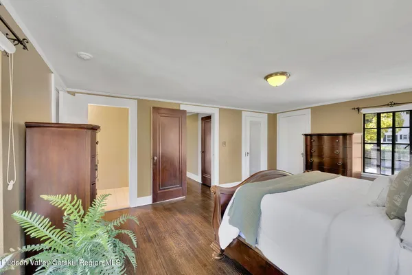 a bedroom with a bed and a potted plant on the dresser