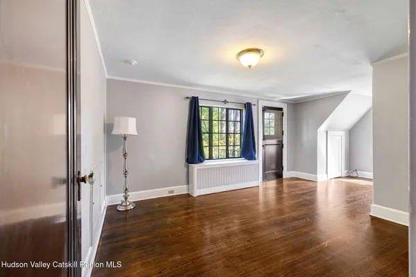 a view of an empty room with window and wooden floor