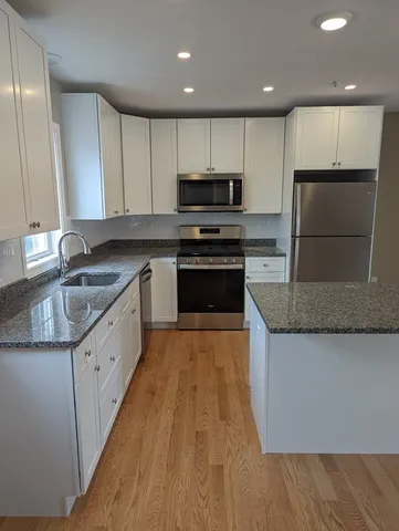 a kitchen with granite countertop a sink a counter top space stainless steel appliances and cabinets