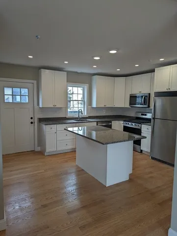 a large kitchen with stainless steel appliances granite countertop a stove a sink and a refrigerator