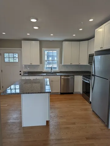 a kitchen with stainless steel appliances granite countertop a stove top oven a sink and a refrigerator