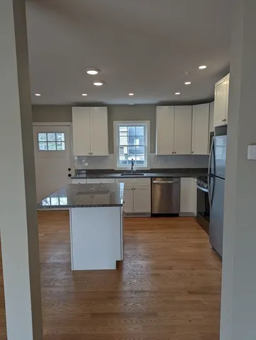 a kitchen with stainless steel appliances granite countertop wooden cabinets a sink a stove a dining table and chairs