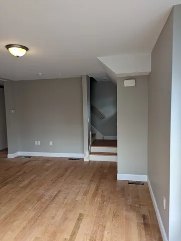 a view of an empty room with wooden floor and closet
