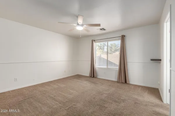 an empty room with chandelier fan and windows