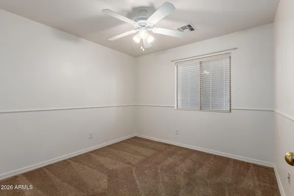 an empty room with a chandelier fan and windows