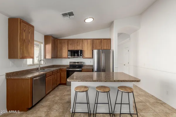 a kitchen with stainless steel appliances granite countertop a sink a stove a microwave a refrigerator and cabinets