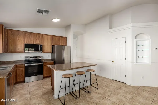 a kitchen with stainless steel appliances granite countertop a stove top oven a sink dishwasher and a refrigerator with wooden cabinets