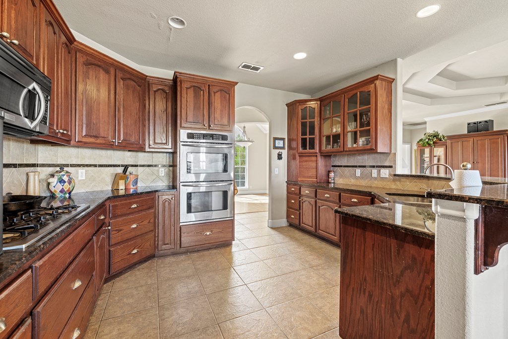 2250 Otte Road Stonewall, TX 78671 - Photo 3 of 35 a kitchen with stainless steel appliances granite countertop a stove top oven a sink dishwasher and a refrigerator