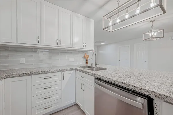 a kitchen with granite countertop white cabinets and stainless steel appliances