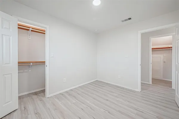 a view of an empty room with wooden floor and closet
