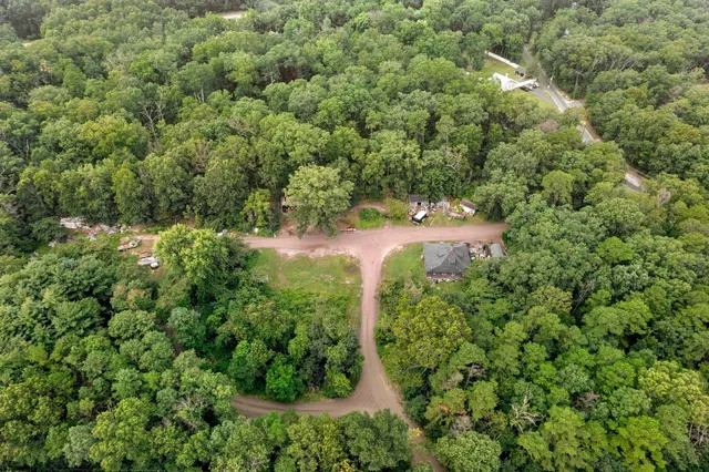 an aerial view of residential house with outdoor space and trees all around