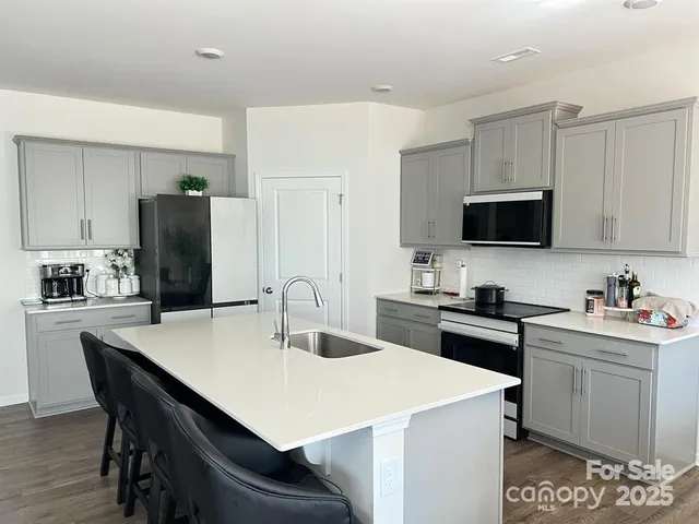a kitchen with a sink a stove a refrigerator and white cabinets