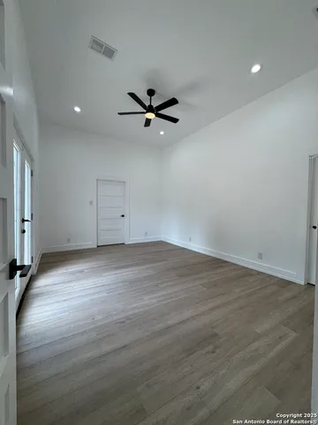 an empty room with wooden floor ceiling fan and window