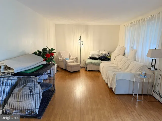 a living room with stainless steel appliances kitchen island granite countertop a stove a sink a refrigerator and white cabinets with wooden floor