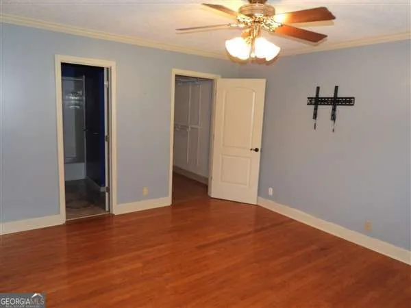 an empty room with wooden floor fan and windows