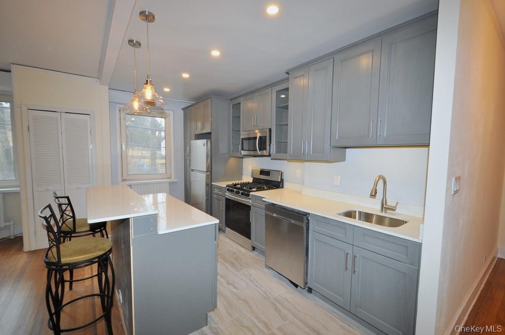 69 Harney Road, Unit 3A Scarsdale, NY 10583 - Photo 8 of 22 Renovated Kitchen with center Island, pendent lighting, Granite Counters, Stainless Steel Appliance including a dishwasher, range, microwave and refrigerator. The wall separating the eat-in-kitchen and living room have been removed and a center Island installed with electric and USB outlets installed to create an open concept.