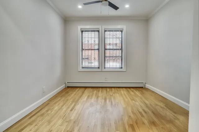 an empty room with wooden floor cabinet and windows