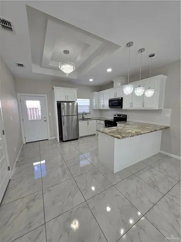 a large kitchen with granite countertop a stove a sink a microwave and a refrigerator