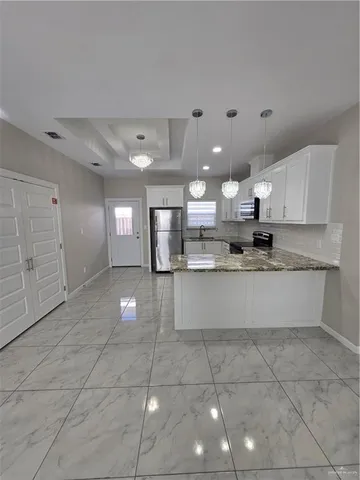 a large kitchen with stainless steel appliances a stove a sink a counter top space and cabinets