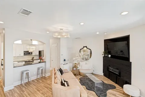 a living room with furniture a flat screen tv and kitchen view