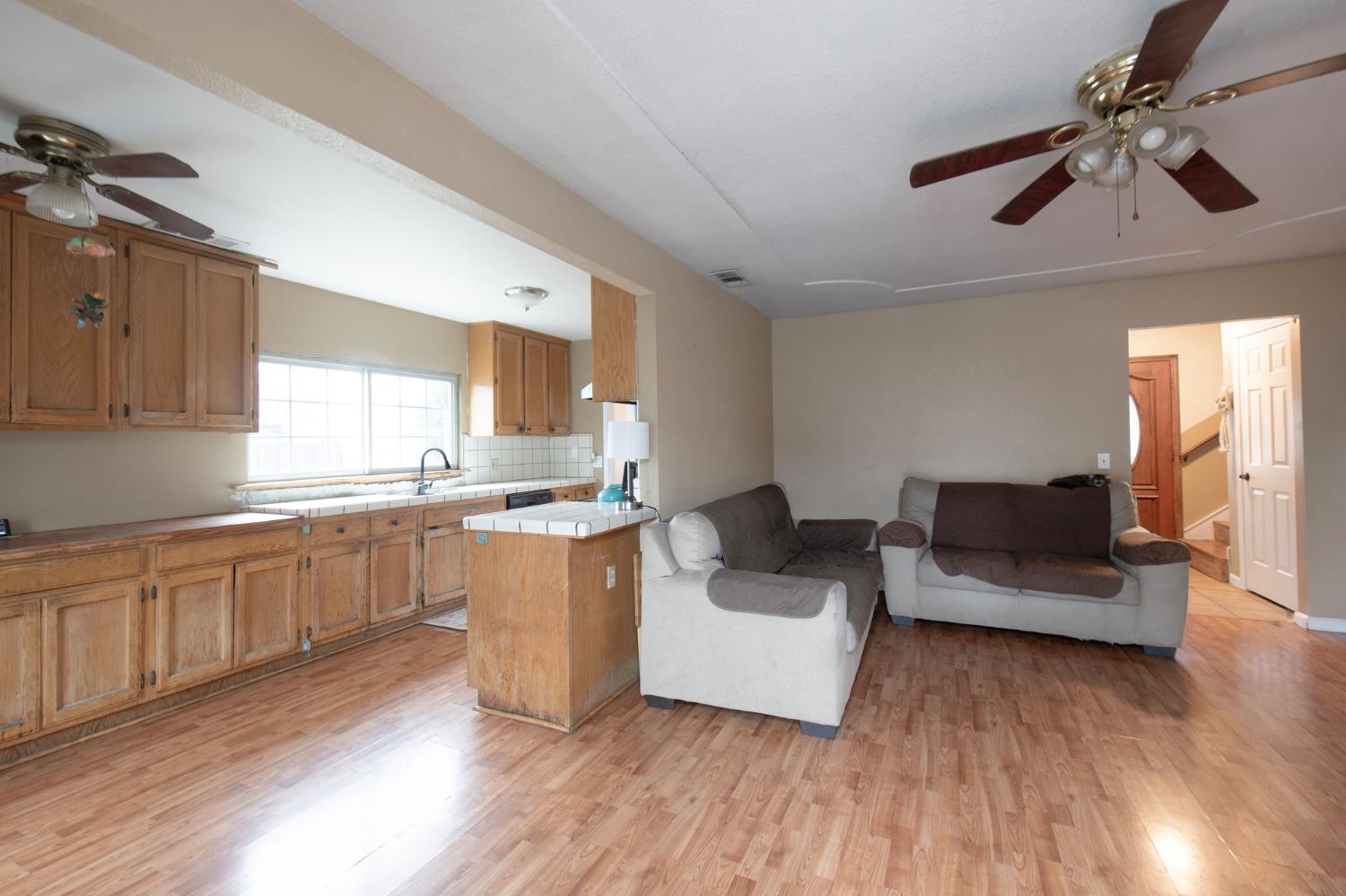 14531 West Kearney Boulevard Kerman, CA 93630 - Photo 11 of 22 a kitchen with a sink dishwasher a stove and white cabinets with wooden floor
