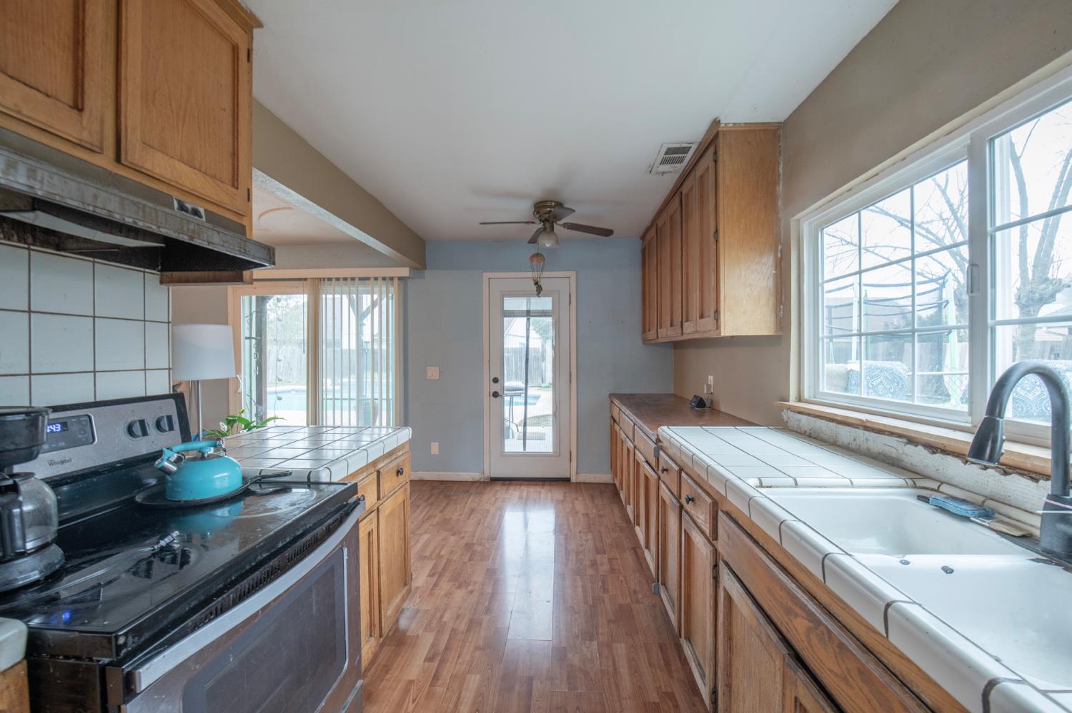 14531 West Kearney Boulevard Kerman, CA 93630 - Photo 5 of 22 a kitchen with granite countertop a stove a sink dishwasher and wooden cabinets with wooden floor