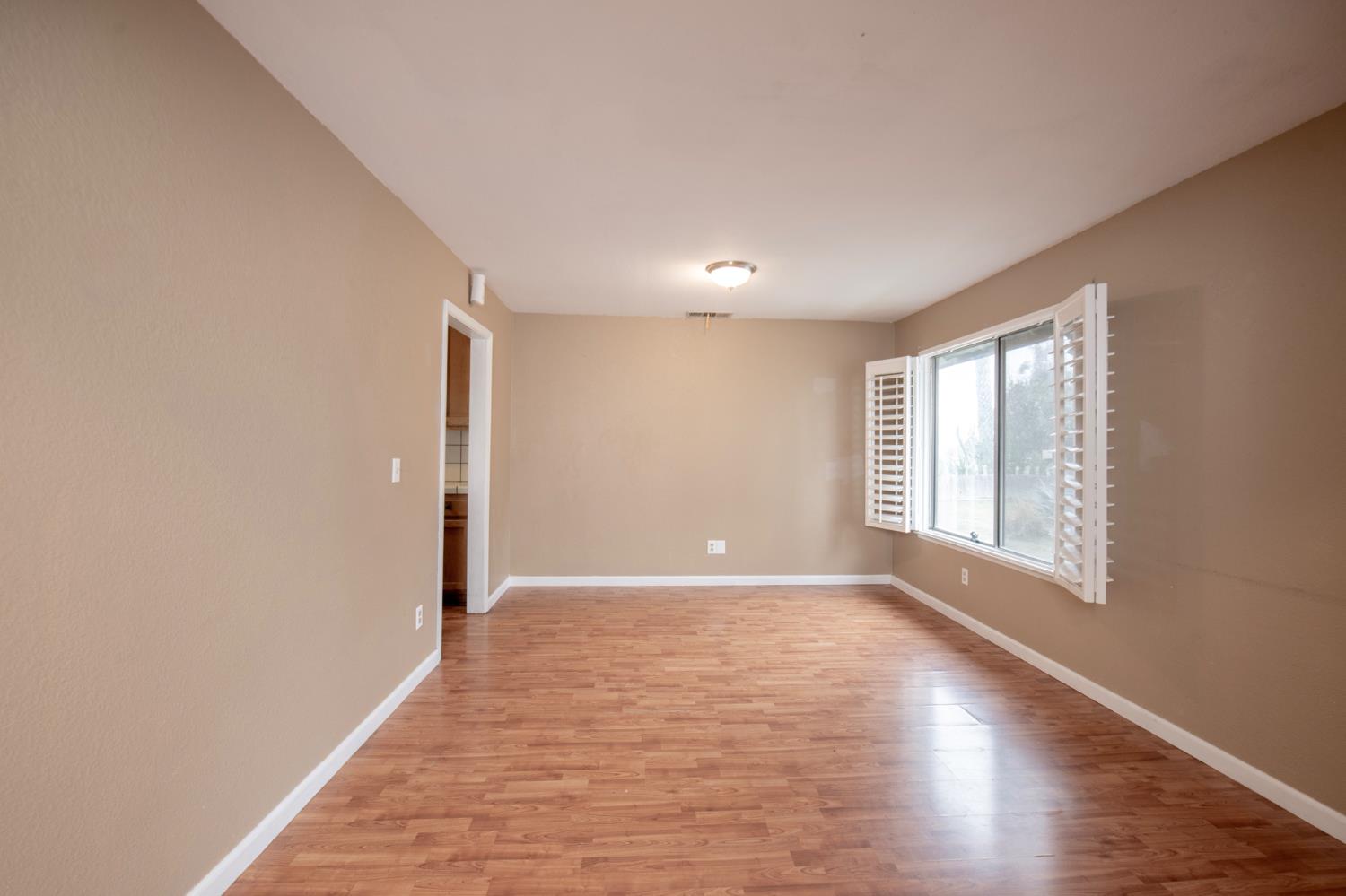 14531 West Kearney Boulevard Kerman, CA 93630 - Photo 9 of 22 a view of an empty room with wooden floor and a window