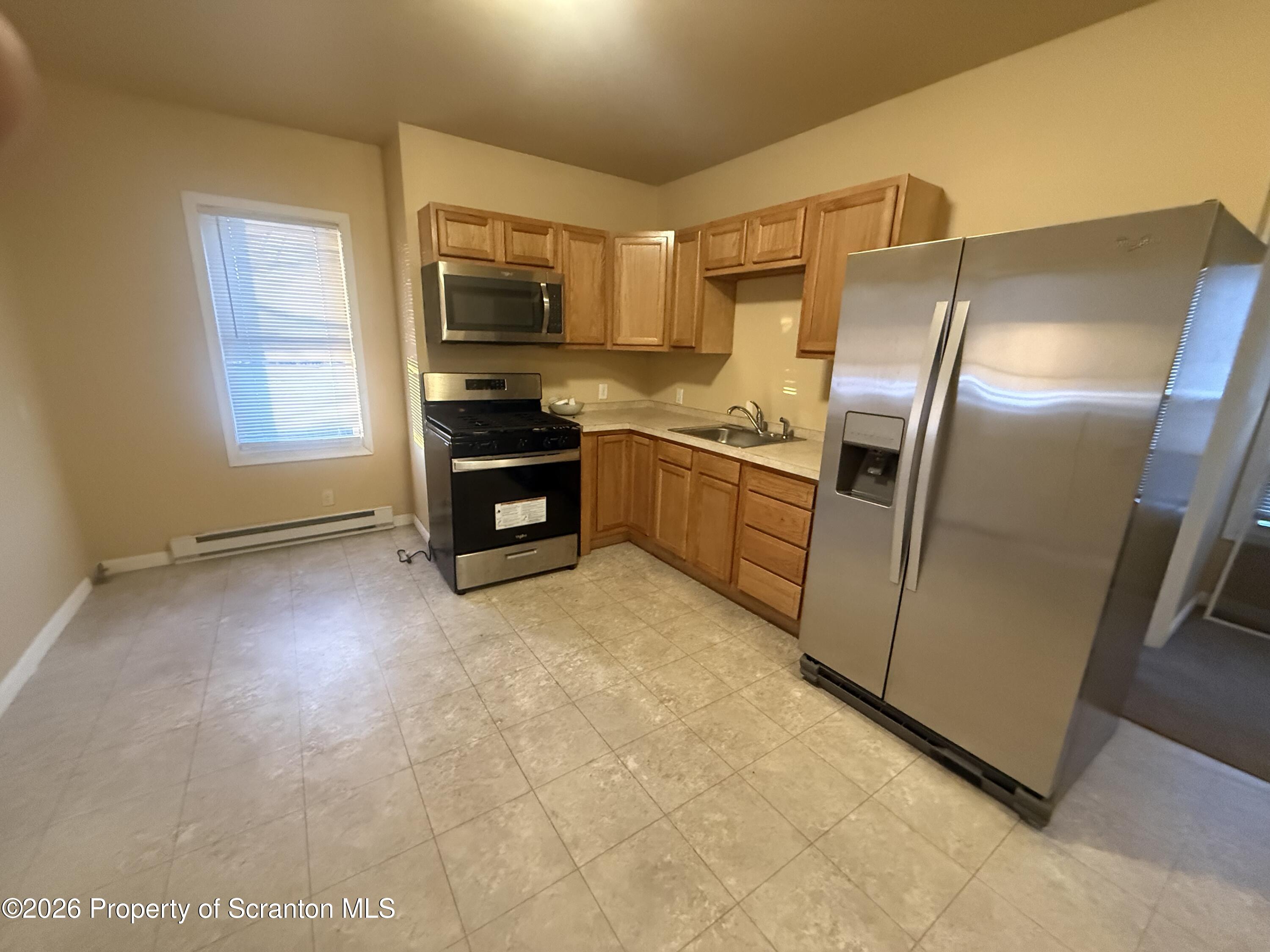 1409 Sanderson Avenue, Unit 2 Scranton, PA 18509 - Photo 3 of 9 a kitchen with granite countertop a refrigerator and a stove top oven