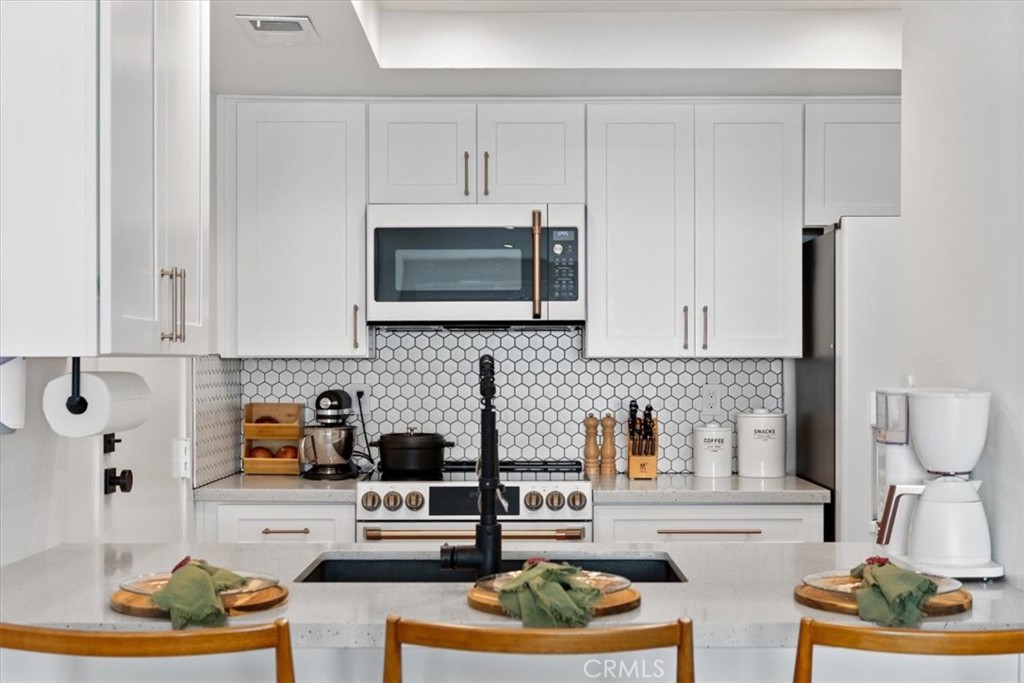 16873 Donwest Tustin, CA 92780 - Photo 12 of 42 a kitchen with stainless steel appliances granite countertop a stove and white cabinets