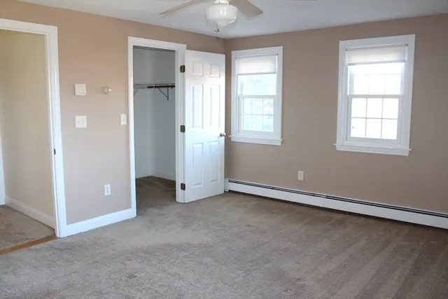an empty room with chandelier fan and windows