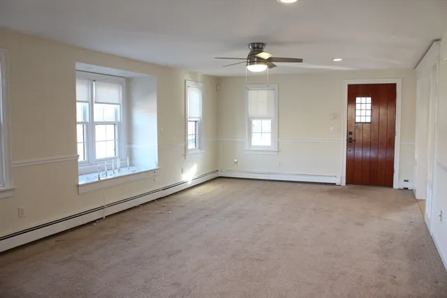 an empty room with windows and chandelier fan