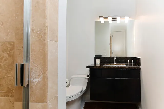 a bathroom with a granite countertop sink toilet and mirror