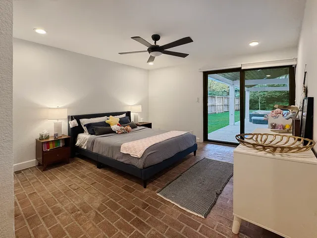 a spacious bedroom with a bed a dresser and a large window