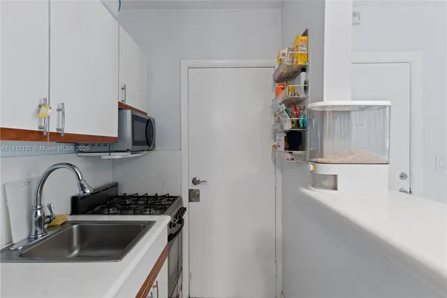 a kitchen with sink a microwave and cabinets