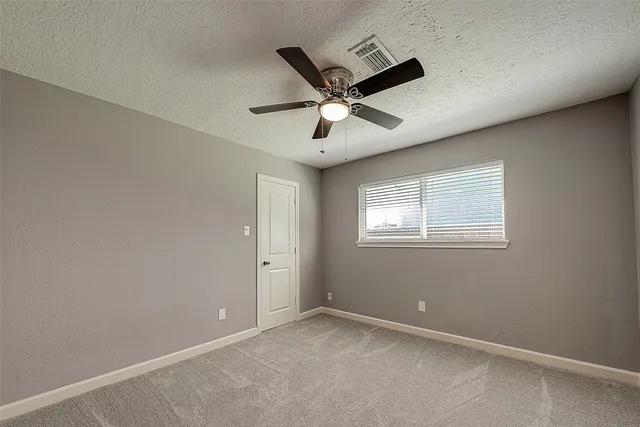 an empty room with a window and a fan