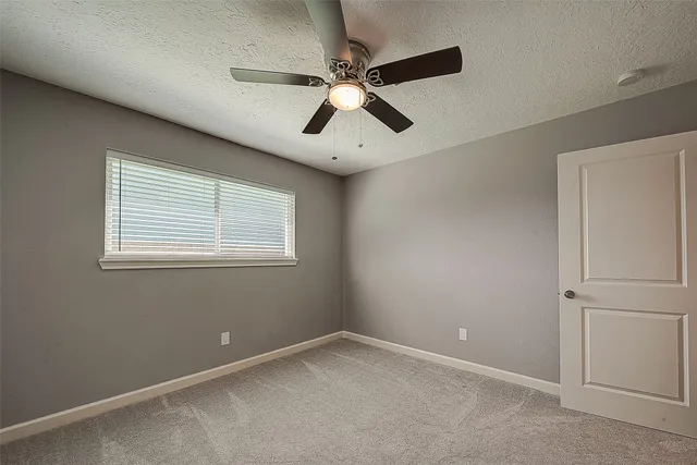 an empty room with a window and a fan