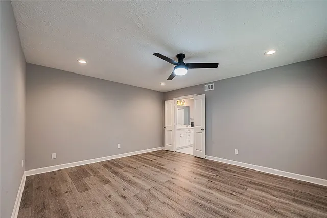 a view of empty room with wooden floor and fan