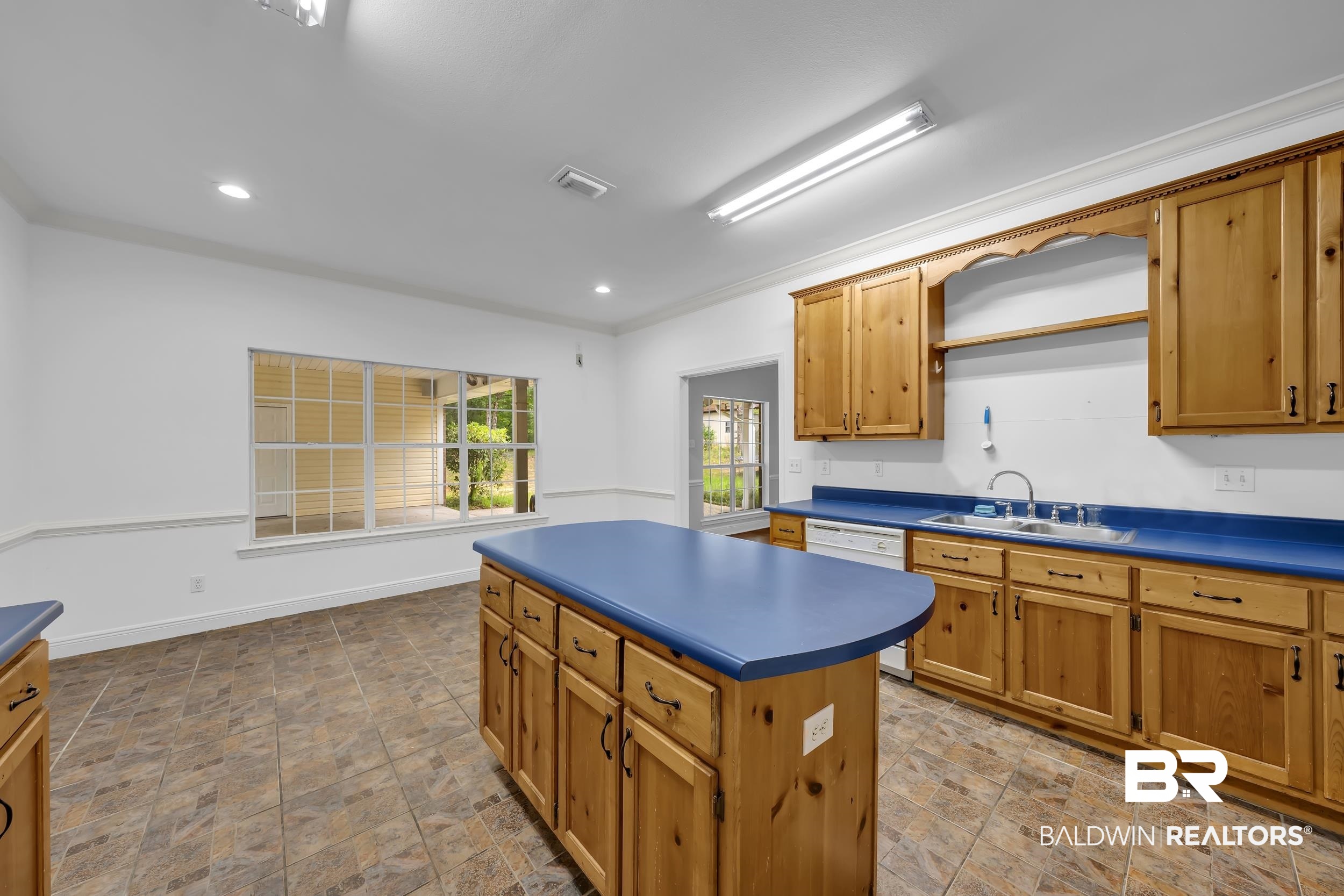 14960 Howells Ferry Road Wilmer, AL 36587 - Photo 10 of 22 Kitchen featuring a central island, wood cabinetry, blue countertops, and tiled flooring