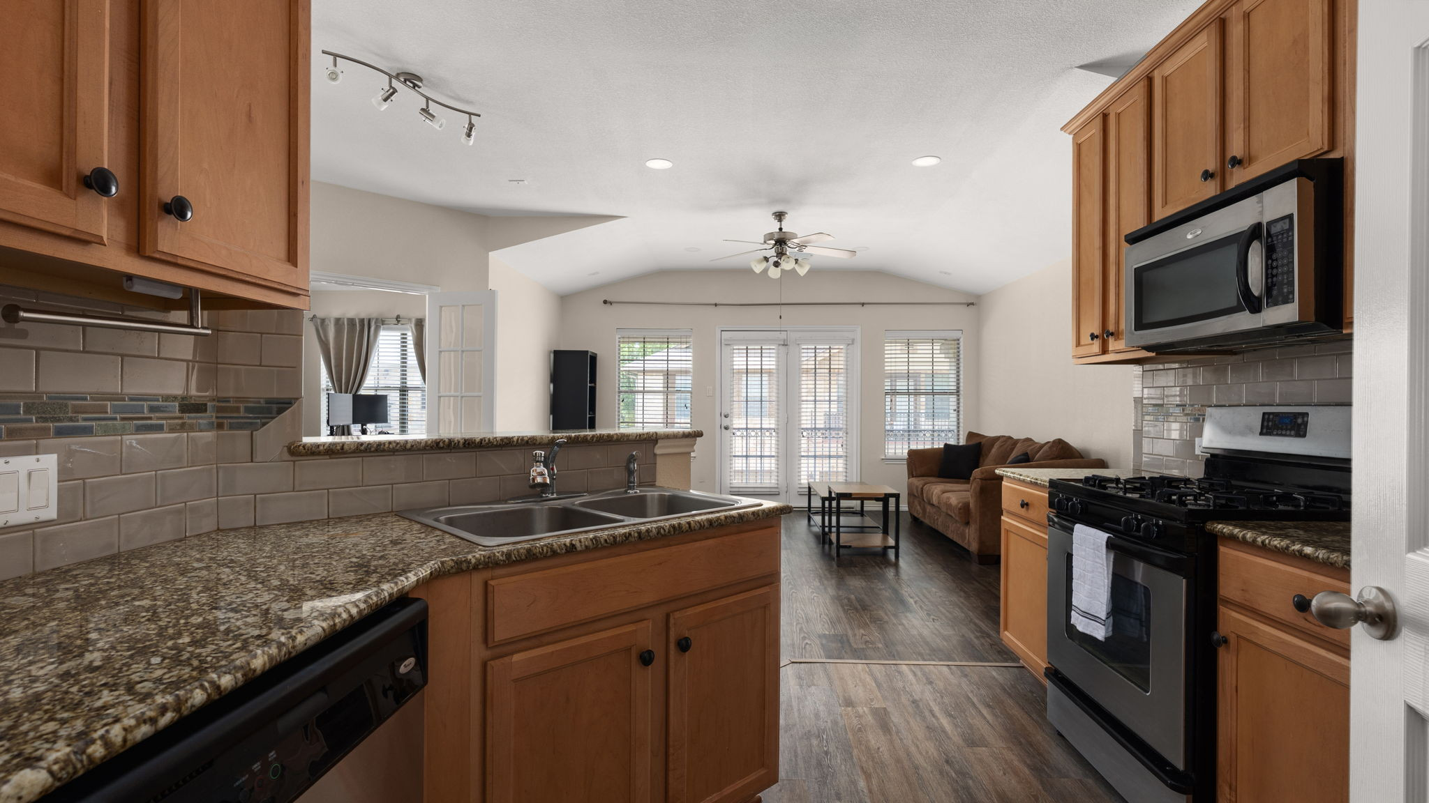 14815 Avery Ranch Boulevard, Unit 1401 Austin, TX 78717 - Photo 26 of 38 Kitchen featuring wood-finish cabinetry, granite-style countertops, and a subway tile backsplash