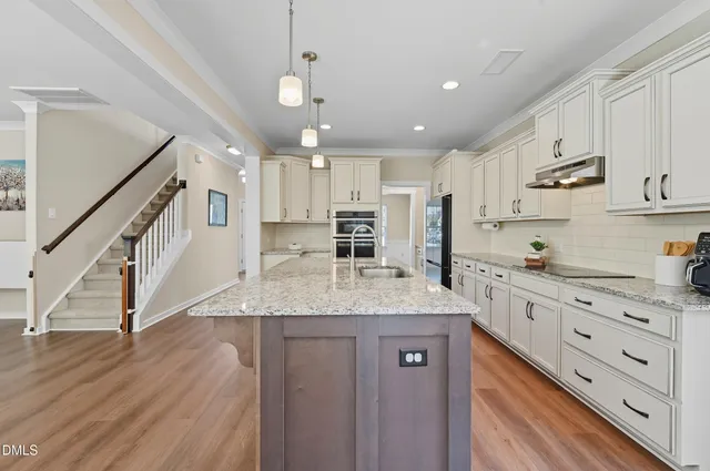 a kitchen with kitchen island granite countertop a sink a counter space appliances and cabinets