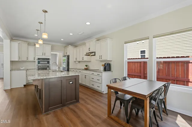a kitchen with stainless steel appliances granite countertop a table chairs sink refrigerator and cabinets